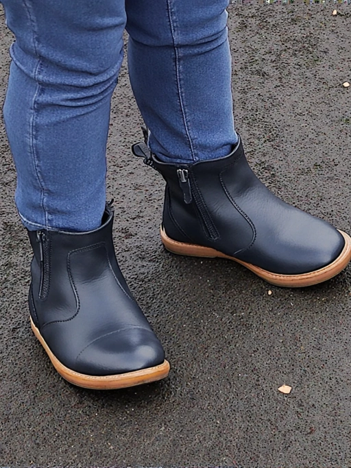 Black Ankle Boots on model with jeans cuff in wet asphalt pavement, lateral side view.
