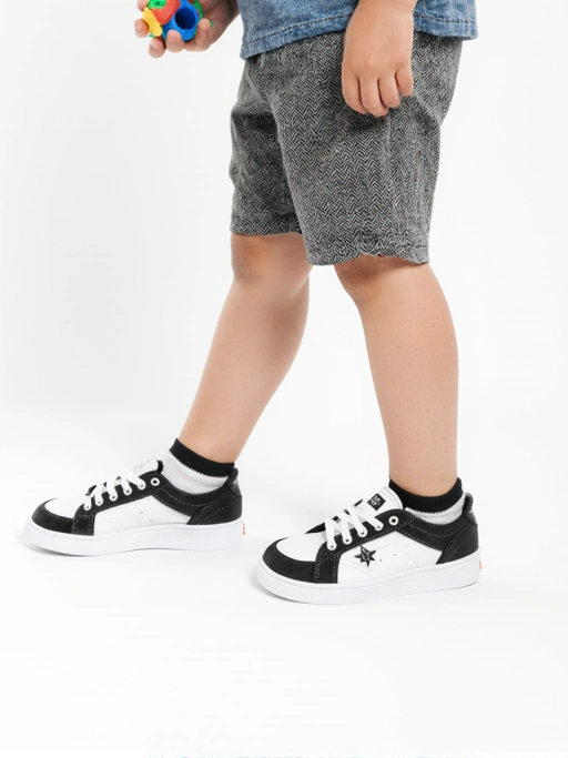 Black and White Low-top Sneakers on child with white crew socks in white infinity background, Lateral Side View