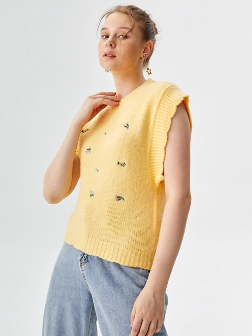 AI模特试穿女士针织上衣(鸟形刺绣)专业版:白人女性工作室模特身着无袖针织上衣,极简白色工作室背景,专业风格。