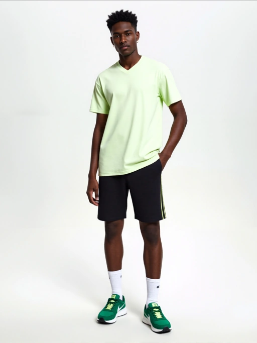 Fotografi Produk AI Profesional untuk Kaos Pria dengan Model Afrika-Amerika menampilkan Model Afrika-Amerika mengenakan kaos di Studio Putih Minimalis, gaya profesional.